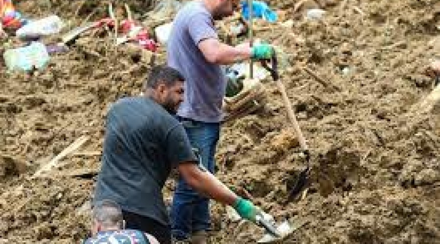 Irmãos cavam a terra em busca do pai que está desaparecido em Petrópolis