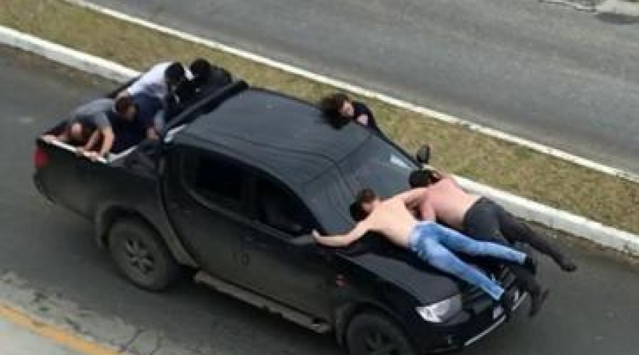 Assaltantes de bancos fogem da polícia com reféns no capô de veículo